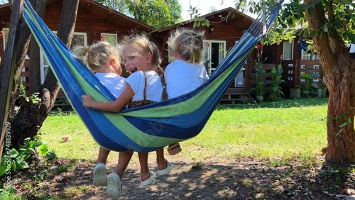 Triplet sisters swinging on a hammock in summer in the yard