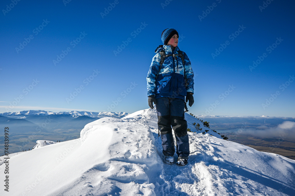 a little boy hiker walks along the snowy ridge of the Western Tatras to Baranec, beautiful view
