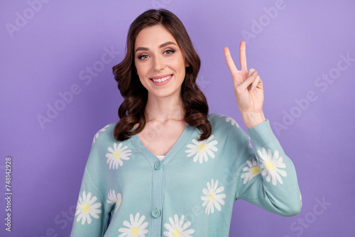 Portrait photo of young friendly girl in blue cardigan make v sign sending hello symbol to you isolated on violet color background
