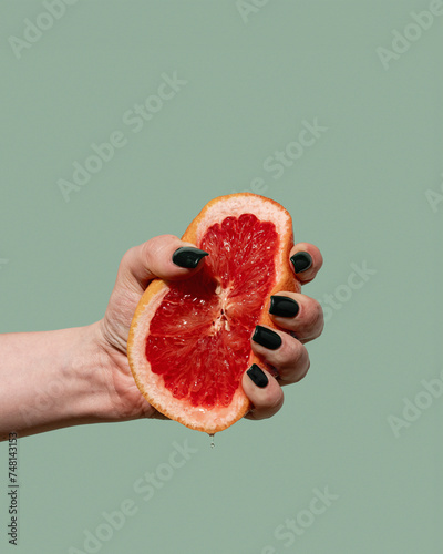 Woman hand holding and squeezing half of the grapefruit