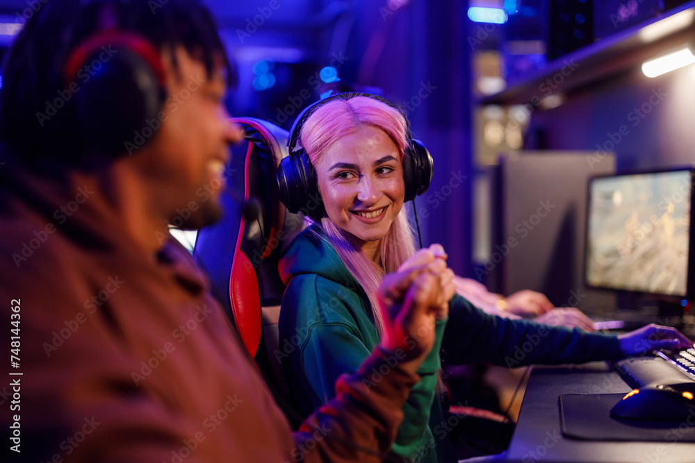 Smiling female professional esport gamer playing games in a gaming lounge Smiling female professional esport gamer playing games in a gaming lounge