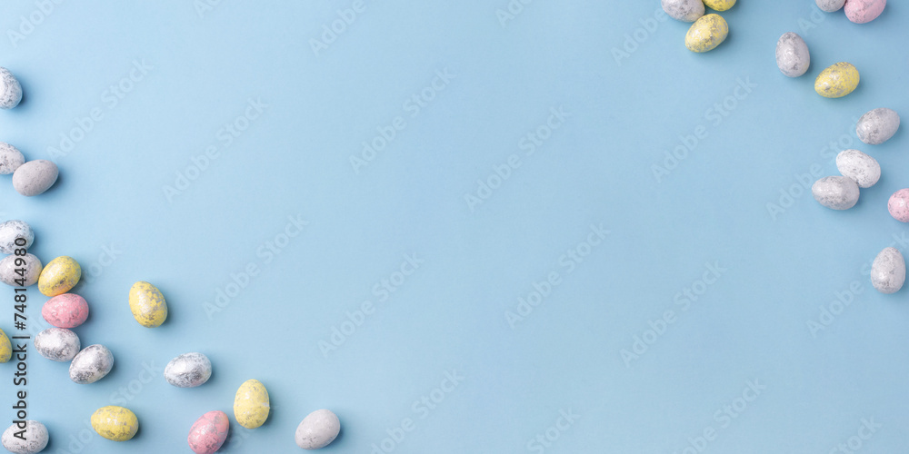 Festive Easter background. Multicoloured Easter eggs on a blue table. Banner with a place for text. Top view. Festive Easter background. Multicoloured Easter eggs on a blue table. Banner with a place for text. Top view.