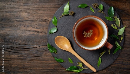 A wooden table set with a cup of tea  tea leaves  and a wooden spoon. The circle of the cup contrasts with the natural elements of wood and plant life. Text space  left