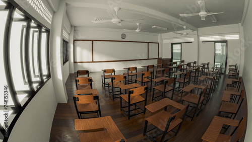 A 3D-rendered panoramic view of an empty classroom with rows of wooden desks and chairs, two ceiling fans, and a long whiteboard on the wall, bathed in natural light.