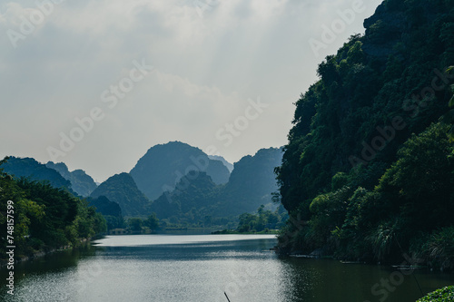 Landscape views of limestone mountains, reflective water and lush greenery of Tran An. A popular spot for tourist to take boat rides while in Northern Vietnam.
