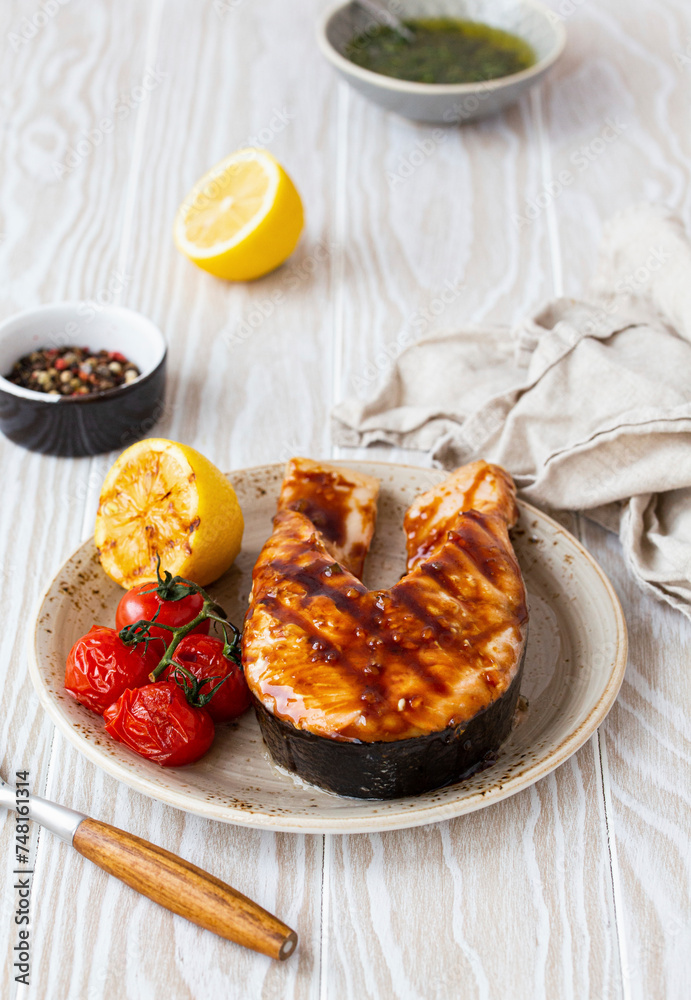 Grilled salmon steak glazed with teriyaki sauce, tomatoes and lemon Grilled salmon steak glazed with teriyaki sauce, tomatoes and lemon