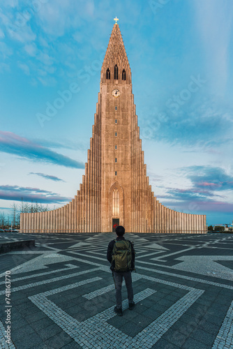 Male backpacker standing and looking at Hallgrimskirkja Lutheran parish church at Reykjavik downtown, Iceland