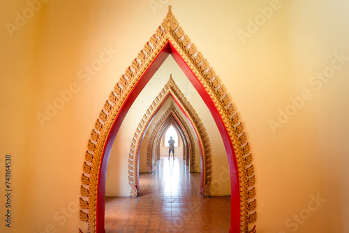 Traditional golden arch door with male tourist in corridor at Wat Tham Sua, Kanchanaburi photo