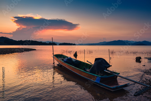 Sunset view of the Kaeng Krachan reservoir with fishing boat and tourist rowing canoe