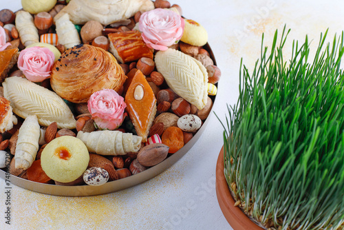 Traditional Azerbaijan holiday Novruz background with green semeni,traditional azerbaijan sweets,shekerbura,qogal,paxlava,mutaki and different nuts and sweets,top view,space for copy