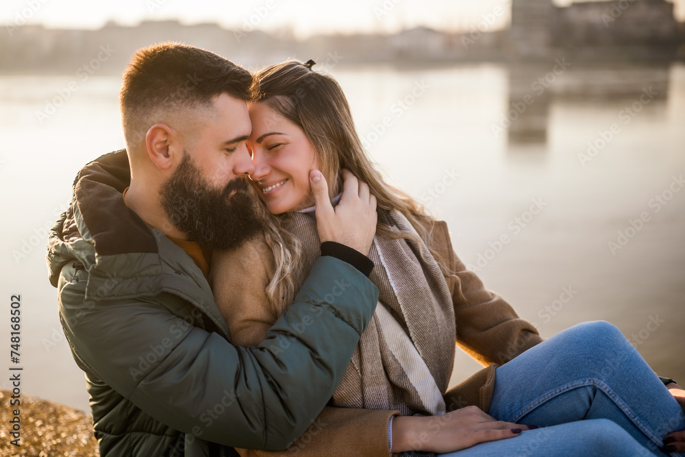 Fototapeta premium Happy couple embracing while enjoy sitting by the river. 