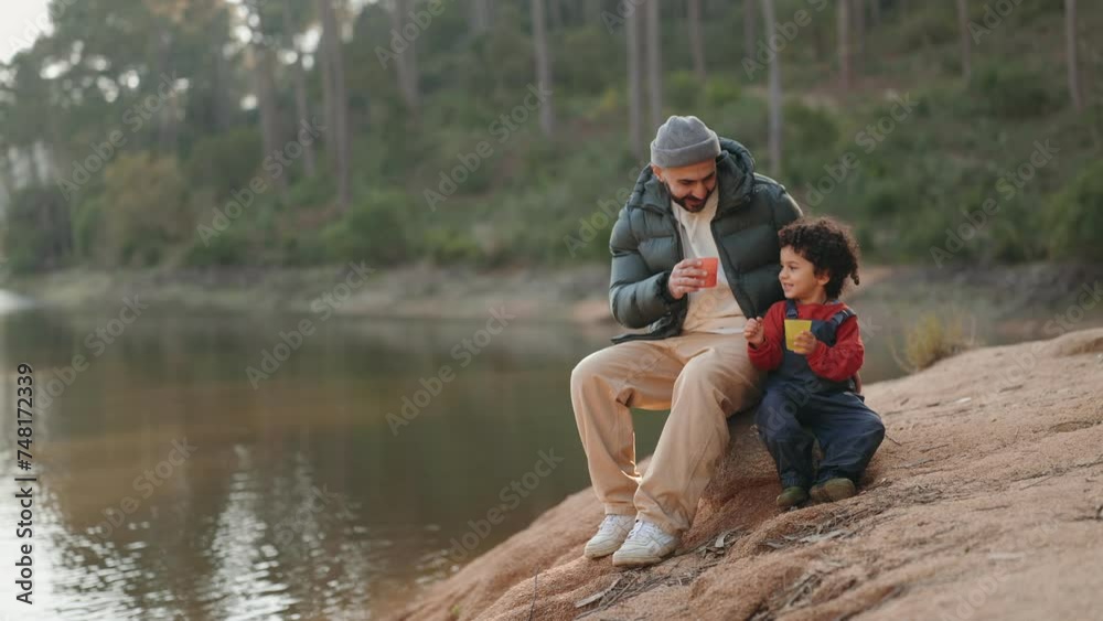 A father and son bond while taking a break and having drinks by a serene lakeside, seated on a wooden stump. A father and son bond while taking a break and having drinks by a serene lakeside, seated on a wooden stump.