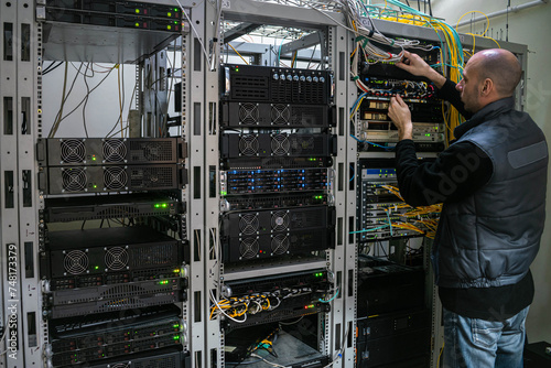 A technician works with patch wires in the server room of a data center. Man supports the technical platform of the Internet provider.