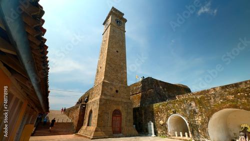 Ancient clock tower in fortress. Action. Beautiful sunny view of stone walls and clock tower in ancient fortress. Ancient fortress with clock tower on sunny summer day photo