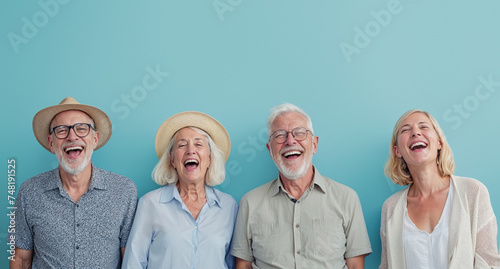 Elderly friends laugh joyfully together outdoors, with two women wearing hats against a pale blue sky background photo