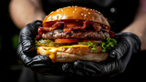 Skillfully gloved hands present a delectable cheeseburger, showcasing the chef's culinary prowess, tantalizing the senses with its savory allure and enticing aroma.
