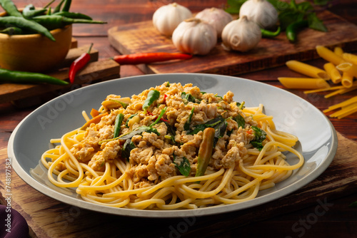 Stir fried spicy spaghetti with minced chicken breast and basil leaves in white plate,Spicy pasta Pad Kra Pao.Healthy Thai fusion food