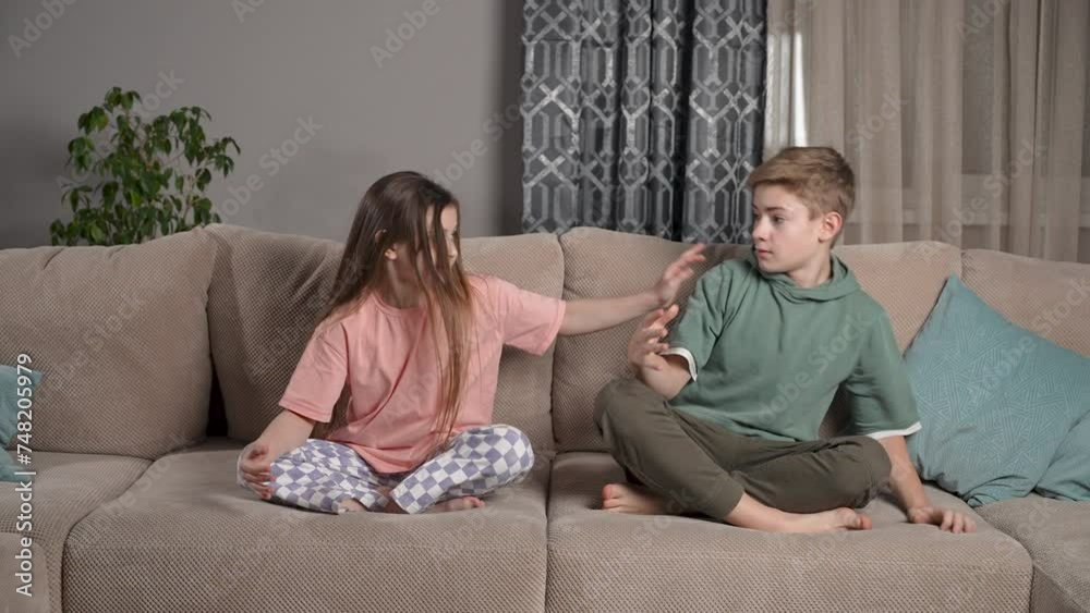 Cute kids girl and boy meditate together, friends sitting on sofa at home and having fun playful pushing each other. Calm mindful sister and healthy brother do yoga exercise relax in lotus pose. Cute kids girl and boy meditate together, friends sitting on sofa at home and having fun playful pushing each other. Calm mindful sister and healthy brother do yoga exercise relax in lotus pose.