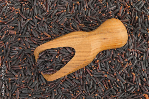 Black rice in a wooden scoop as a background. Top view. Flat lay © kolesnikovserg