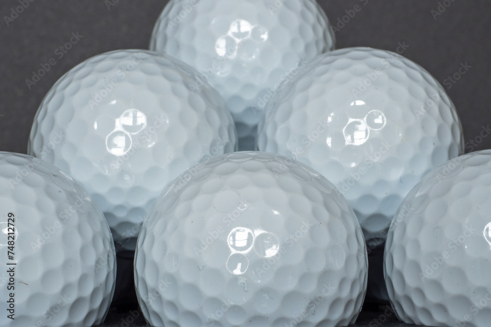Close-up image of some plain white golf unbranded golf balls stacked up upon each other in front of a black background. Close-up image of some plain white golf unbranded golf balls stacked up upon each other in front of a black background.