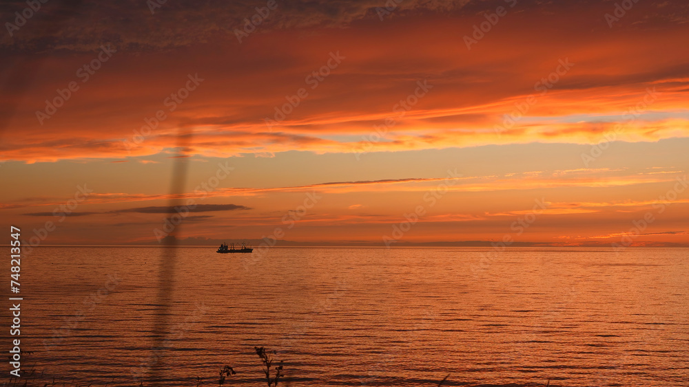 Beautiful seascape with sunset sky and ship on horizon. Clip. Magnificent view of sea sunset with red clouds and ship on horizon. Red sunset with beautiful sea and ship