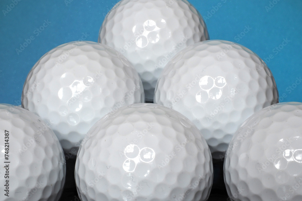 Close-up image of several plain white golf balls stacked up upon each other with a blue background Close-up image of several plain white golf balls stacked up upon each other with a blue background