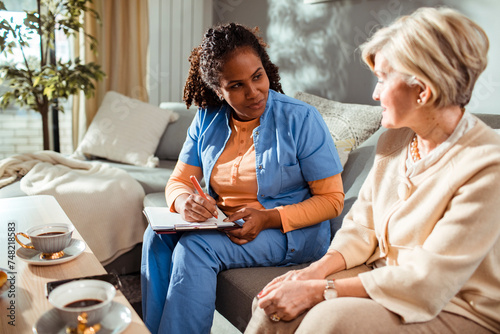 Senior woman talking to caregiver at home photo