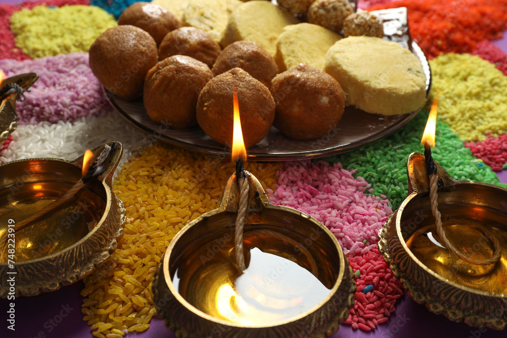 Diwali celebration. Tasty Indian sweets, diya lamps and colorful rangoli on table, closeup Diwali celebration. Tasty Indian sweets, diya lamps and colorful rangoli on table, closeup
