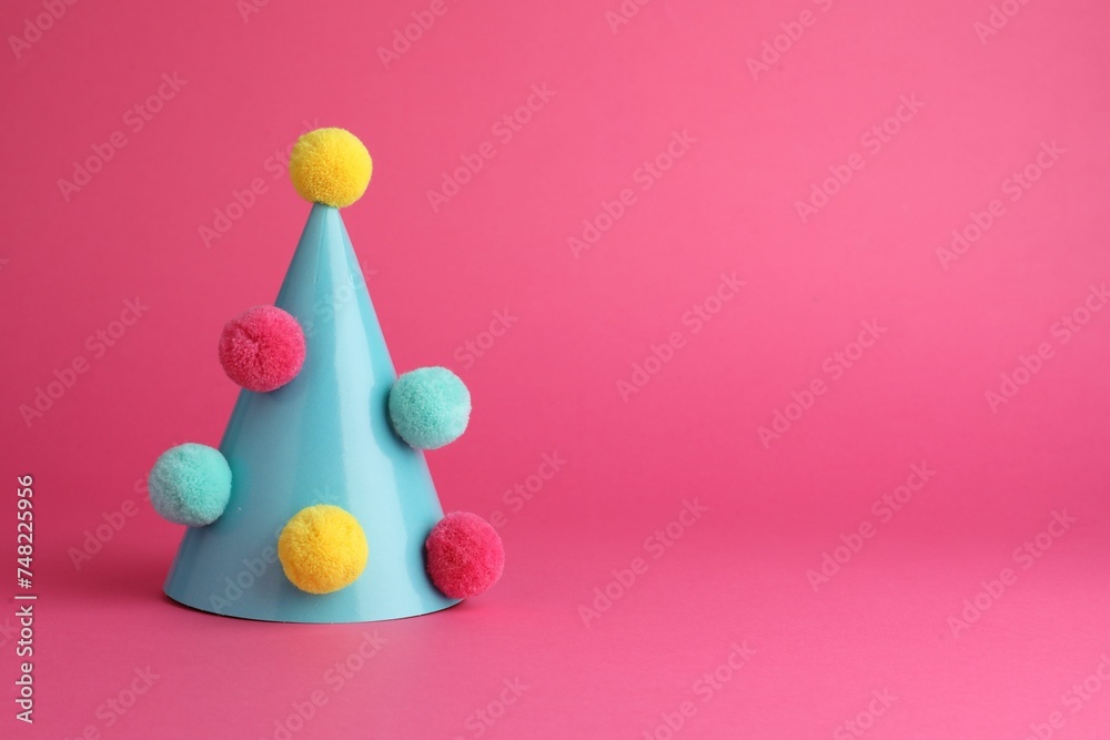 One light blue party hat with pompoms on pink background. Space for text