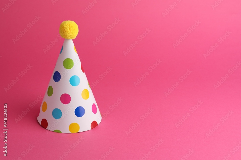 One beautiful party hat with pompom on pink background, space for text