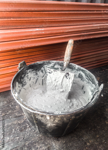 Bucket full white adhesive mortar ready for applicate photo