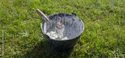 Bucket full white adhesive mortar ready for applicate photo