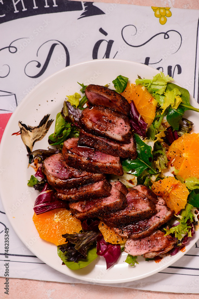 Fried duck breast in honey soy glaze with mixed salad and oranges.top veiw. Fried duck breast in honey soy glaze with mixed salad and oranges.top veiw.