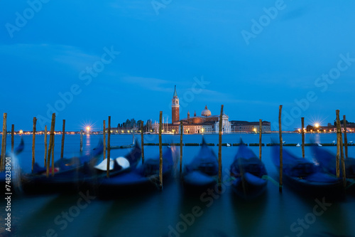 Venetian Gondolas bobbing in the night with the san giorgio maggiore Island at background