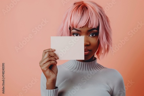 Portrait of a African American person with pink hair holding a blank card sign. 