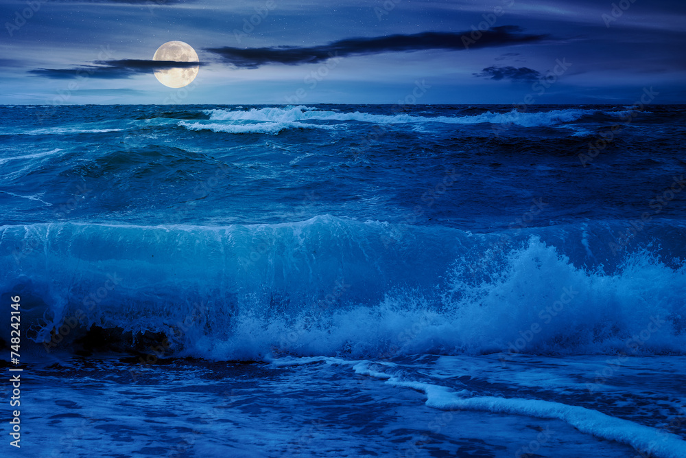 dramatic seascape at night. waves crashing on the beach in full moon light