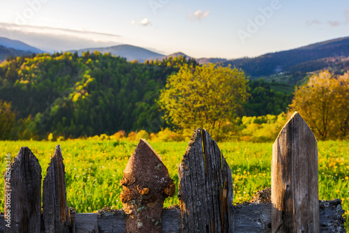 Fototapeta Naklejka Na Ścianę i Meble -  weathered wooden fence. mountainous rural landscape of transcarpathia, ukraine in spring blurred in the distance. carpathian countryside with forested rolling hill beneath a sky evening light