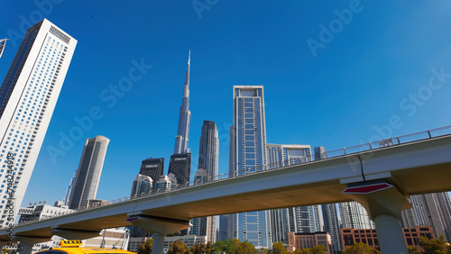 Dubai city with street and bridge with driving cars. Action. Clear blue sky and skyscrapers of the city center.
