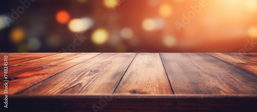 A close-up shot of a wooden table top with a blurry background showcasing ambient lights in soft focus.