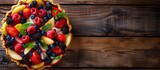 A delicious fruit tart is placed on a rustic wooden table. The golden crust is filled with colorful fresh fruits, creating a visually appealing dessert.