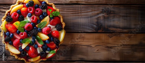 A delicious fruit tart is placed on a rustic wooden table. The golden crust is filled with colorful fresh fruits, creating a visually appealing dessert.
