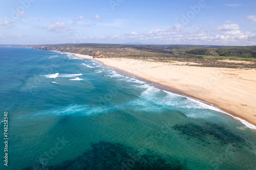 ein beliebter Strand mit Wellen für Surfer an der Atlantikküste von Portugal bei schönem Wetter aus der Vogelperspektive über dem Meer