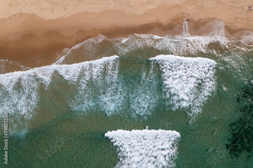 ein beliebter Strand mit Wellen für Surfer an der Atlantikküste von Portugal bei schönem Wetter aus der Vogelperspektive über dem Meer