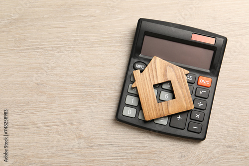 Mortgage concept. House model and calculator on wooden table, top view with space for text