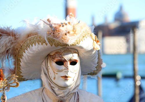 Masked person with white clothes and mask with unrecognizable face during the celebration of the Venice Carnival photo