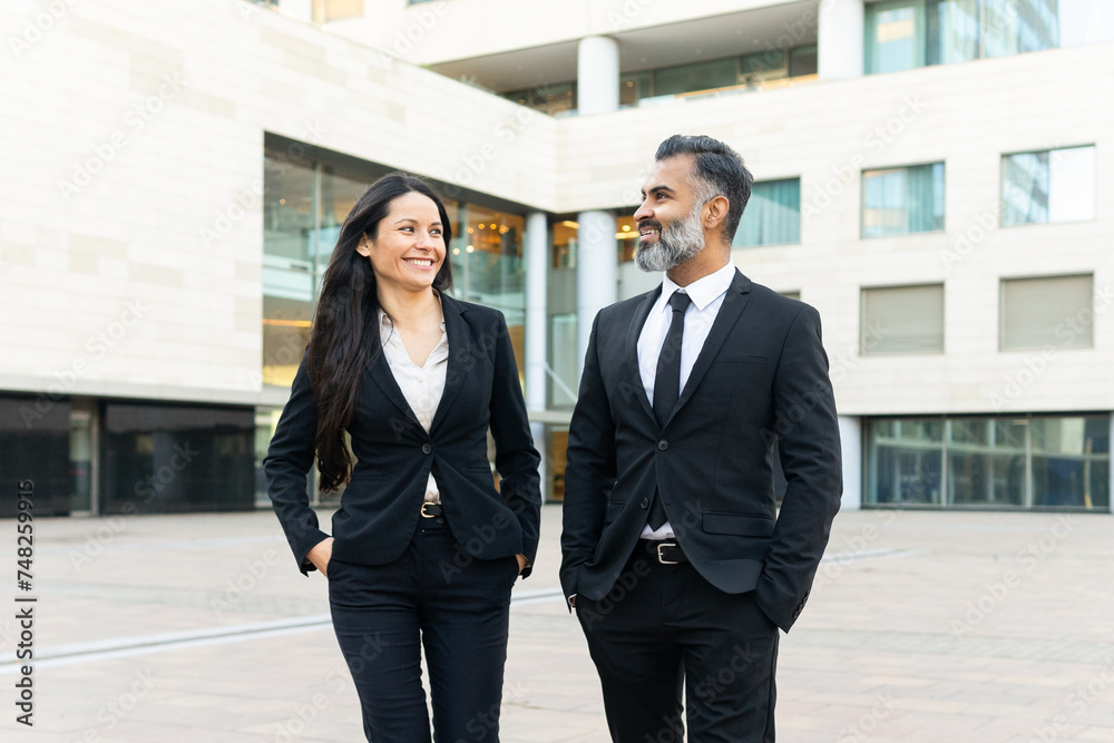Professional colleagues walking and smiling outside office Professional colleagues walking and smiling outside office