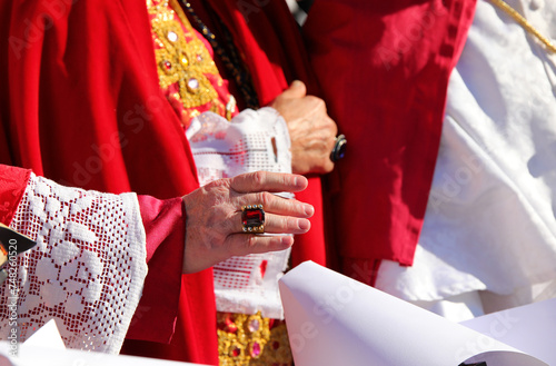 priest with a ring with a red ruby while giving the blessing to the faithful photo