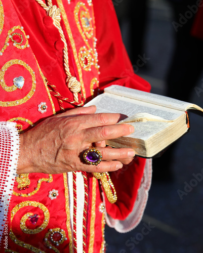 bible with the sacred scriptures in the hands of the bishop with a ring with a precious stone while he gives the blessing to the faithful