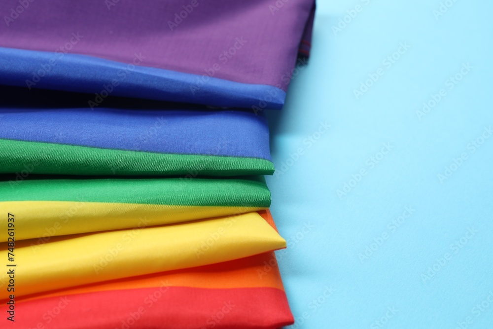 Rainbow LGBT flag on light blue background, closeup. Space for text