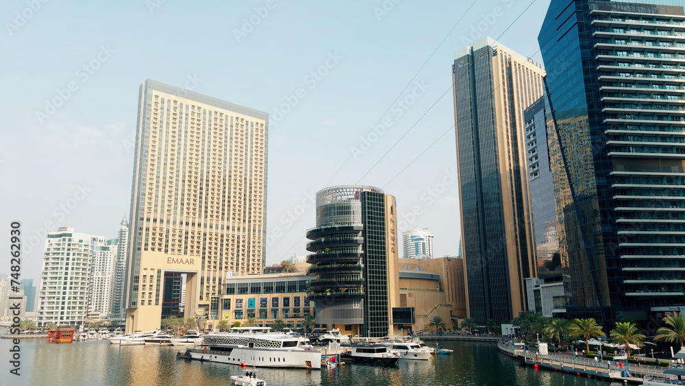 A view of the beautiful city of Dubai and the water canal. Action. Sailing boats and sunny embankment.